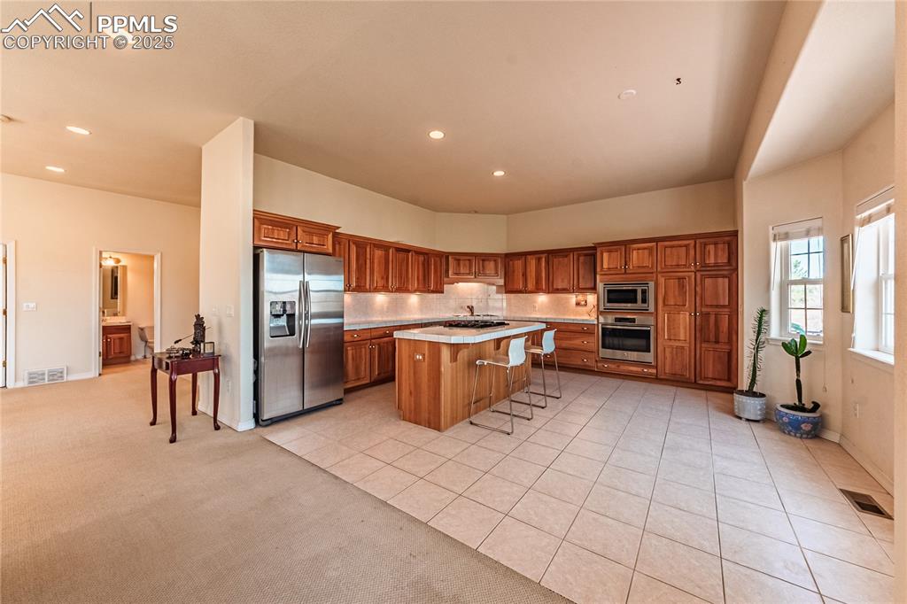 Kitchen with stainless steel appliances, visible vents, a breakfast bar, and brown cabinetry