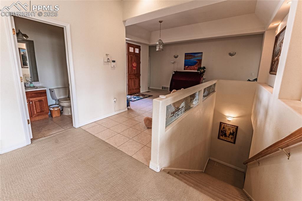 Stairs with visible vents, carpet, tile patterned flooring, and baseboards