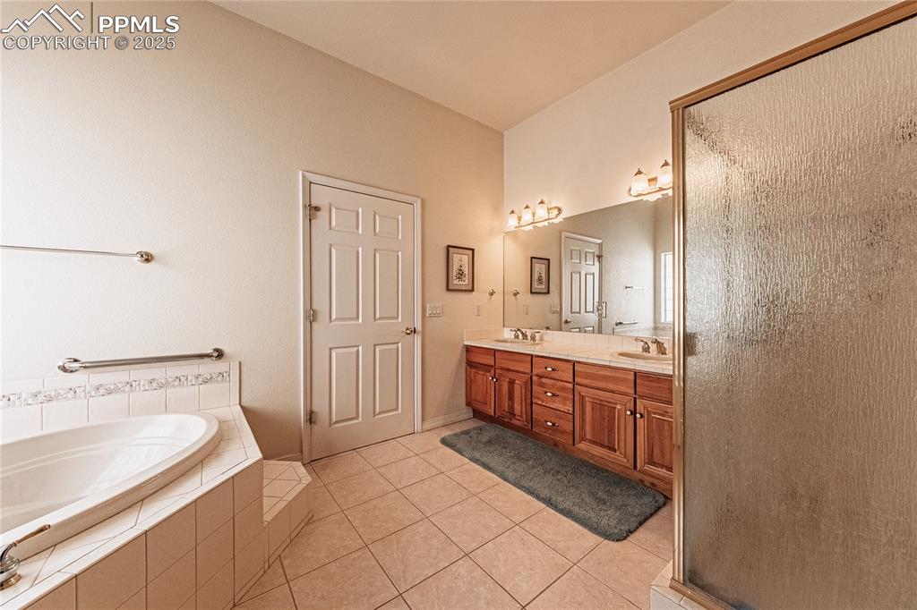 Bathroom with a bath, a shower with door, a sink, tile patterned floors, and double vanity