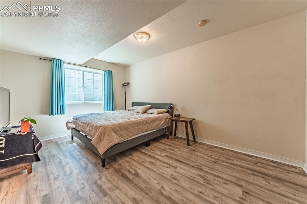 Bedroom featuring baseboards, a textured ceiling, and wood finished floors