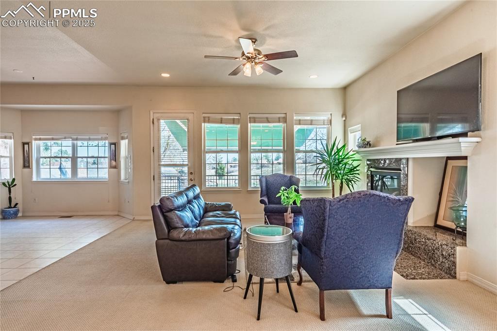 Carpeted living room featuring ceiling fan, recessed lighting, a high end fireplace, and baseboards