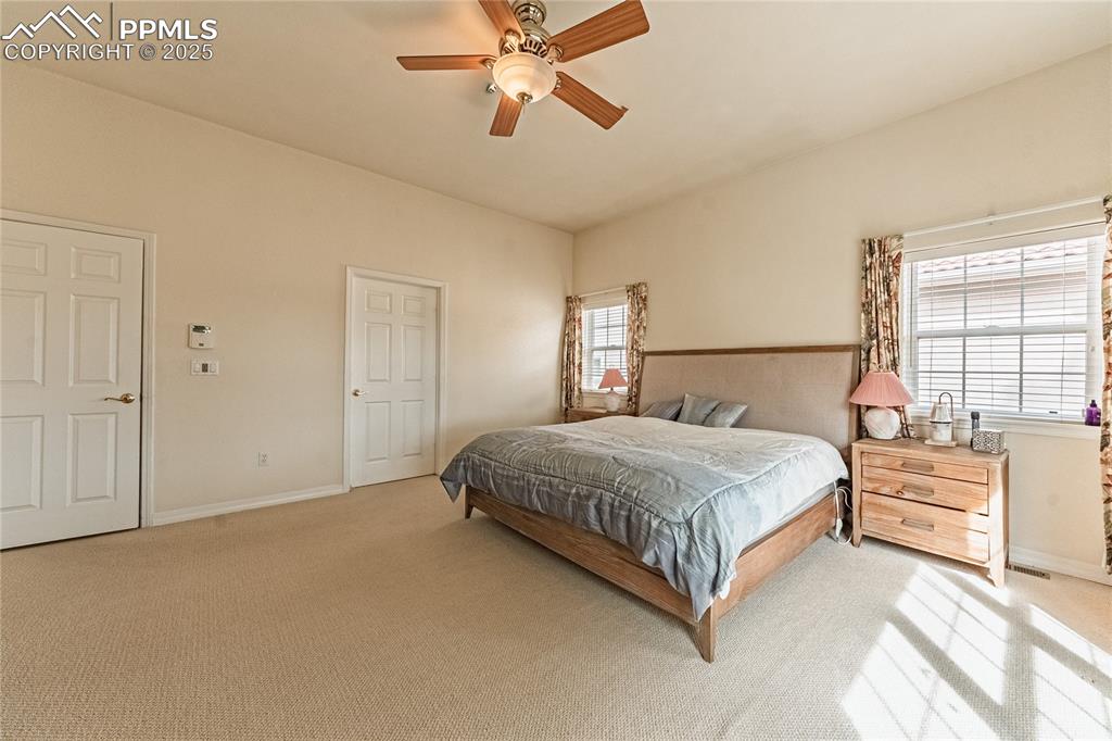 Bedroom featuring light colored carpet, baseboards, and ceiling fan