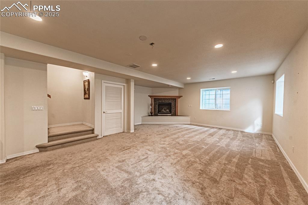 Basement featuring baseboards, recessed lighting, carpet floors, visible vents, and a high end fireplace