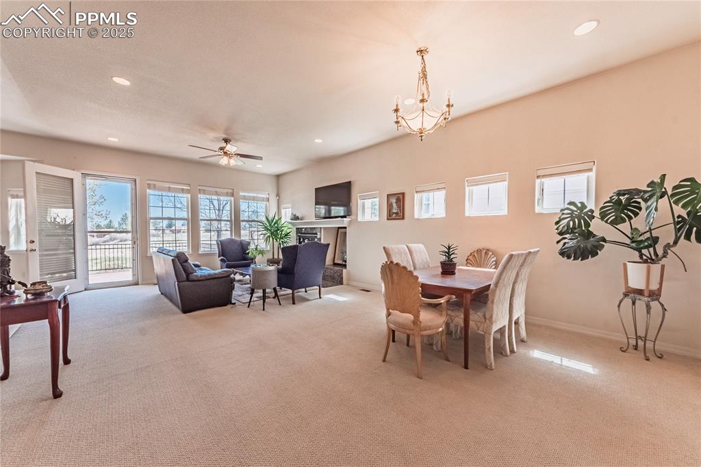 Carpeted dining space with ceiling fan with notable chandelier, baseboards, and recessed lighting