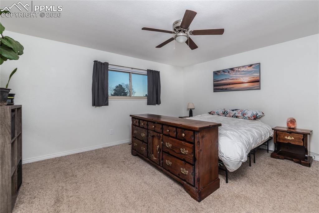 Bedroom with light colored carpet and a ceiling fan