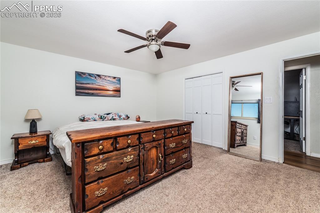 Bedroom featuring ceiling fan, a closet, and light colored carpet