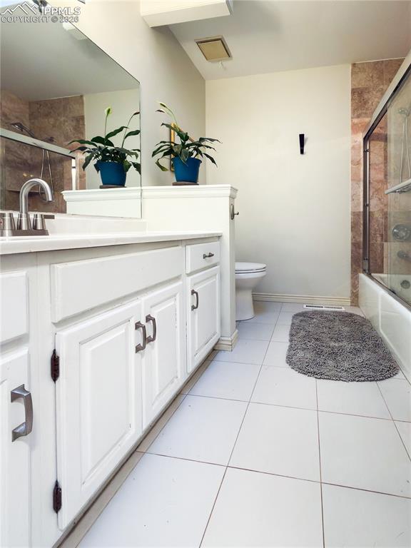 Bathroom with vanity, shower / bath combination with glass door, and light tile patterned floors