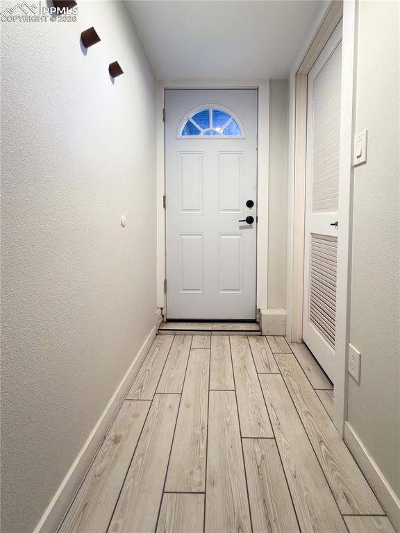 Doorway to outside featuring wood finished floors and a textured wall