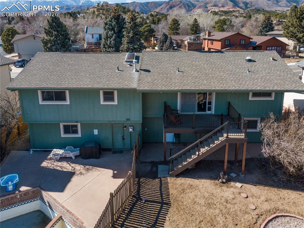Rear view of property with roof with shingles, a mountain view, and a patio