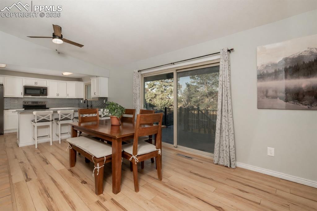 Dining space with lofted ceiling, a ceiling fan, and light wood finished floors