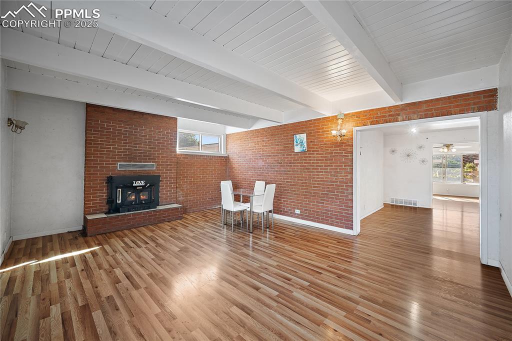  Living room with brick wall, healthy amount of natural light, fire place and beam ceiling