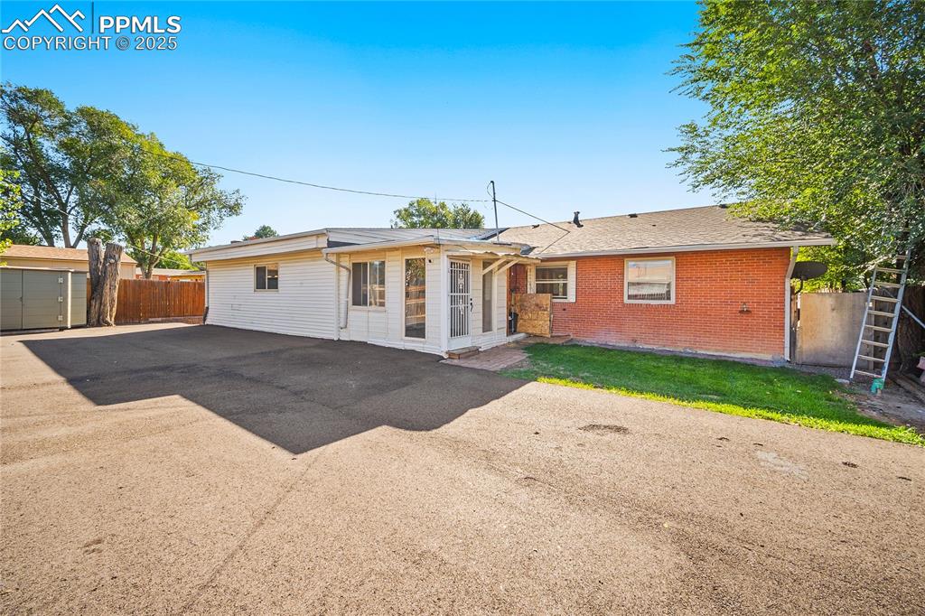 Rear view of house featuring brick siding and roof with shingles