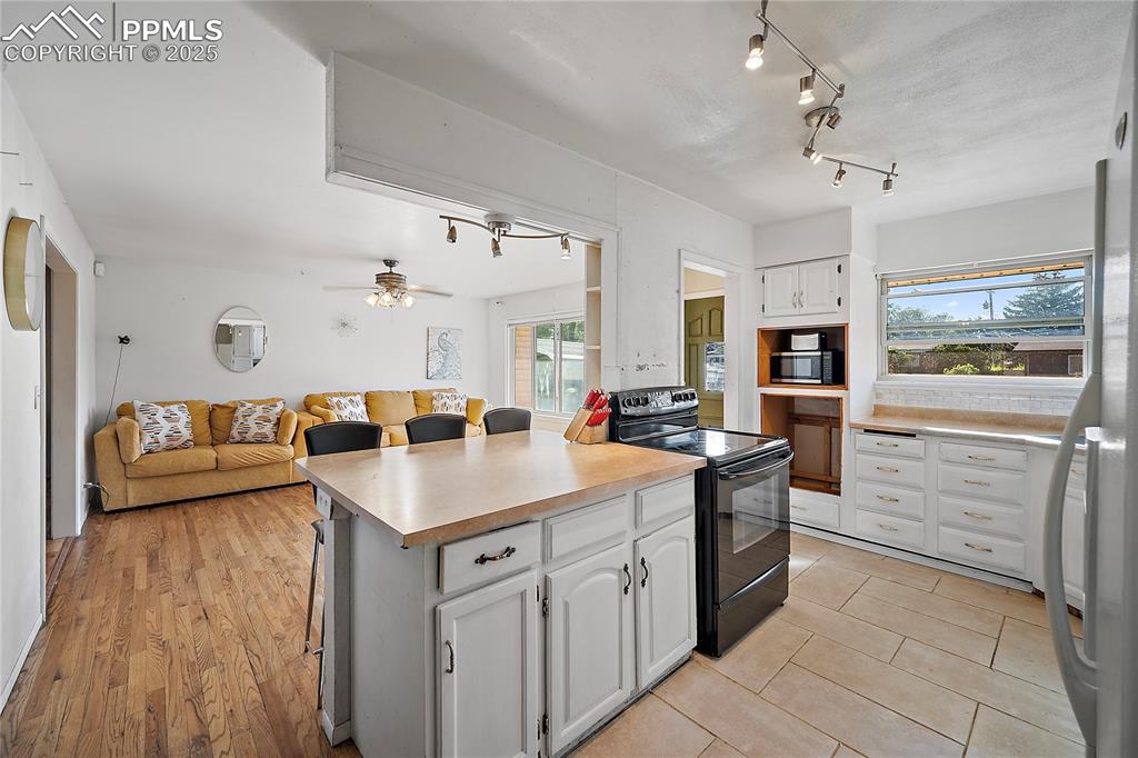 Kitchen featuring white cabinets, open floor plan, ample amount of natural light