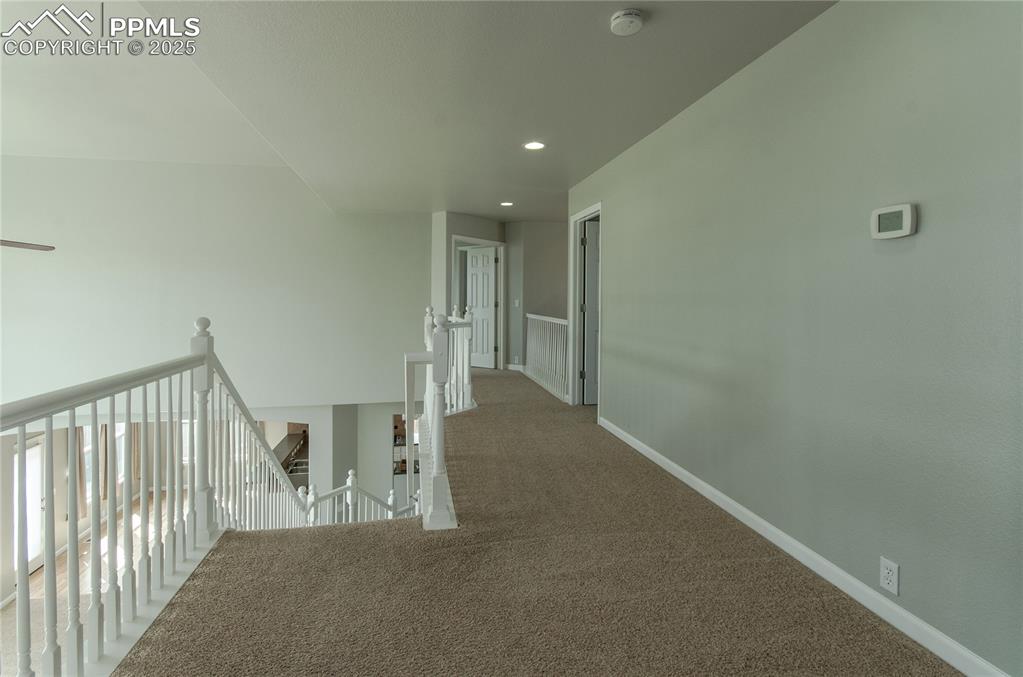 Hallway with an upstairs landing, carpet flooring, and recessed lighting