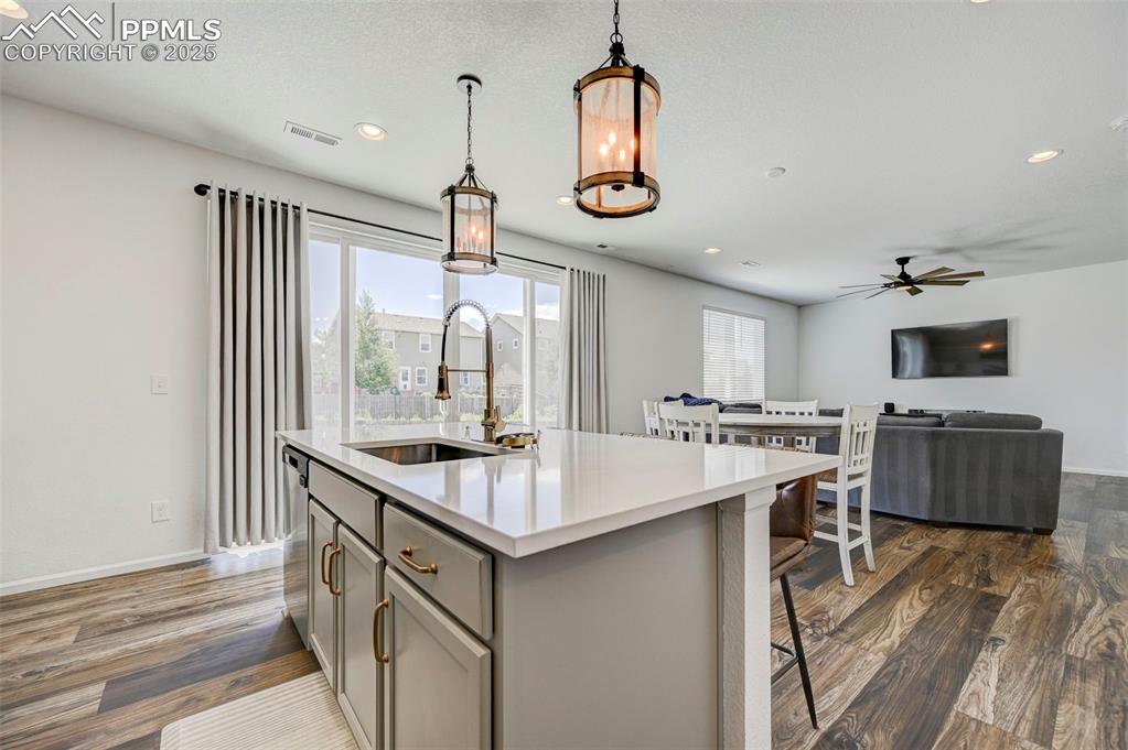 Kitchen featuring gray cabinets, ceiling fan, pendant lighting, dark wood-type flooring, and light countertops