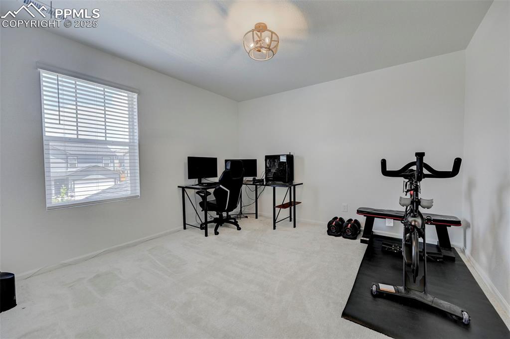 Workout room with a chandelier and carpet flooring