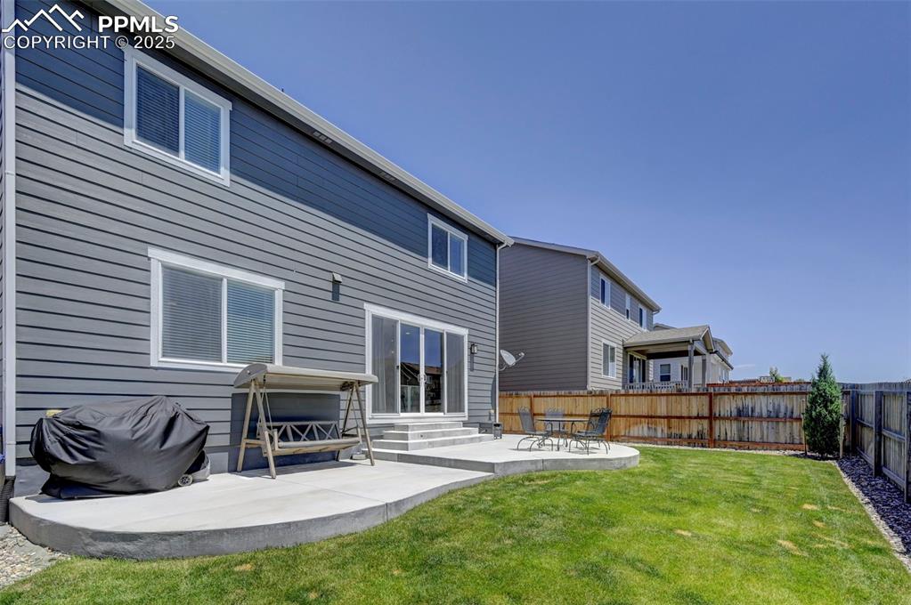Back of house featuring entry steps, a fenced backyard, and a patio