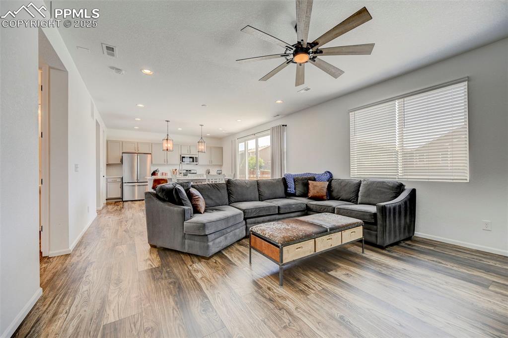 Living area featuring light wood-style flooring, a ceiling fan, and recessed lighting