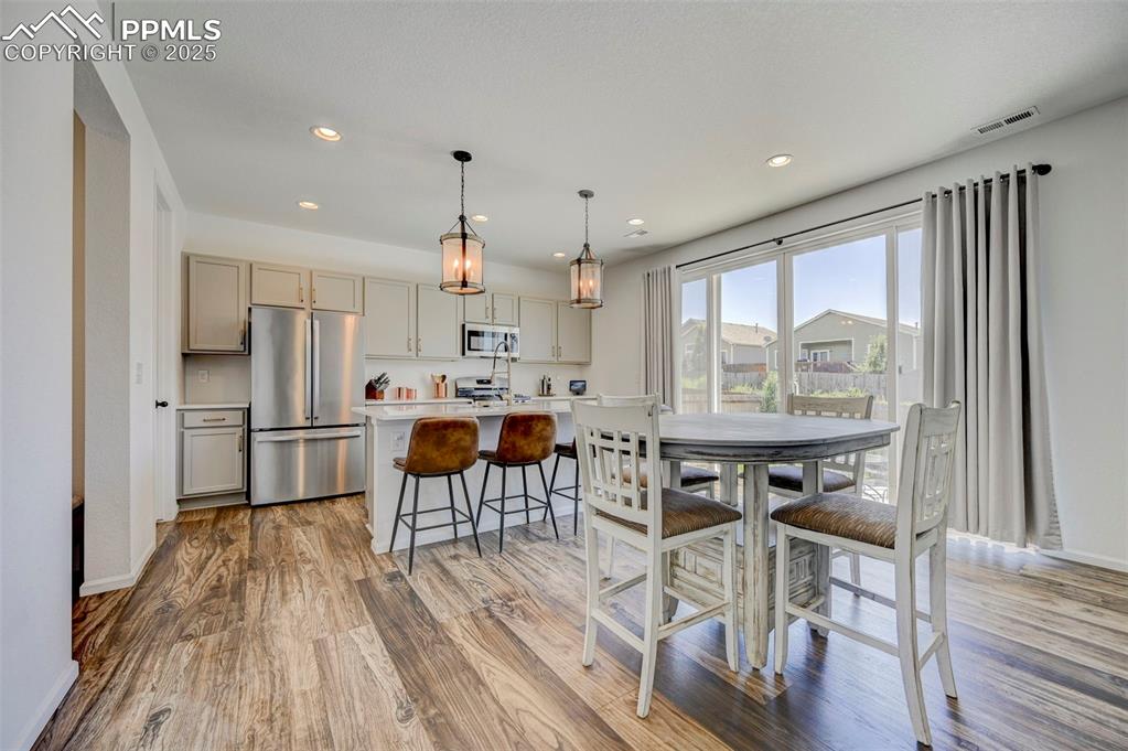 Kitchen featuring stainless steel appliances, light countertops, light wood finished floors, recessed lighting, and a kitchen breakfast bar