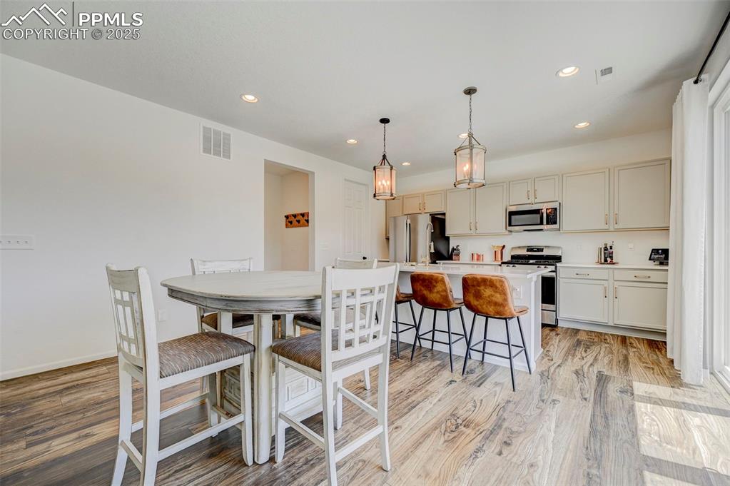 Kitchen with appliances with stainless steel finishes, light wood-style floors, recessed lighting, a breakfast bar area, and light countertops