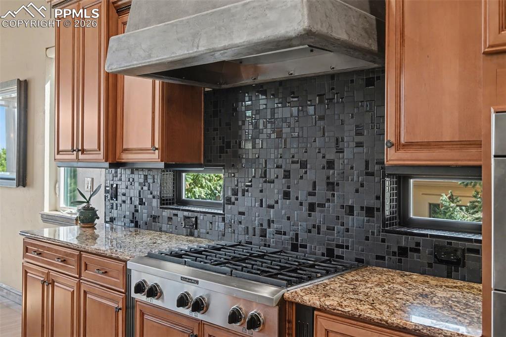Professional-grade appliances, striking stone countertops, and contrasting full height tile backsplash