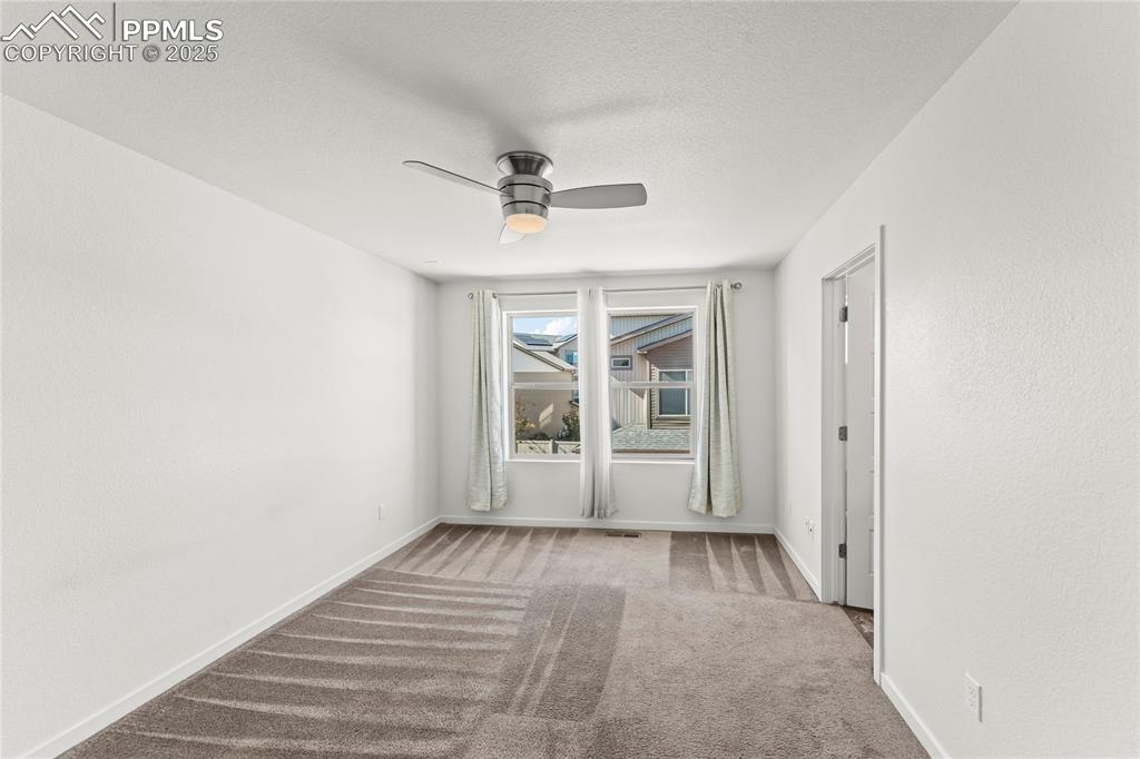 Spare room featuring light colored carpet, ceiling fan, and a textured ceiling