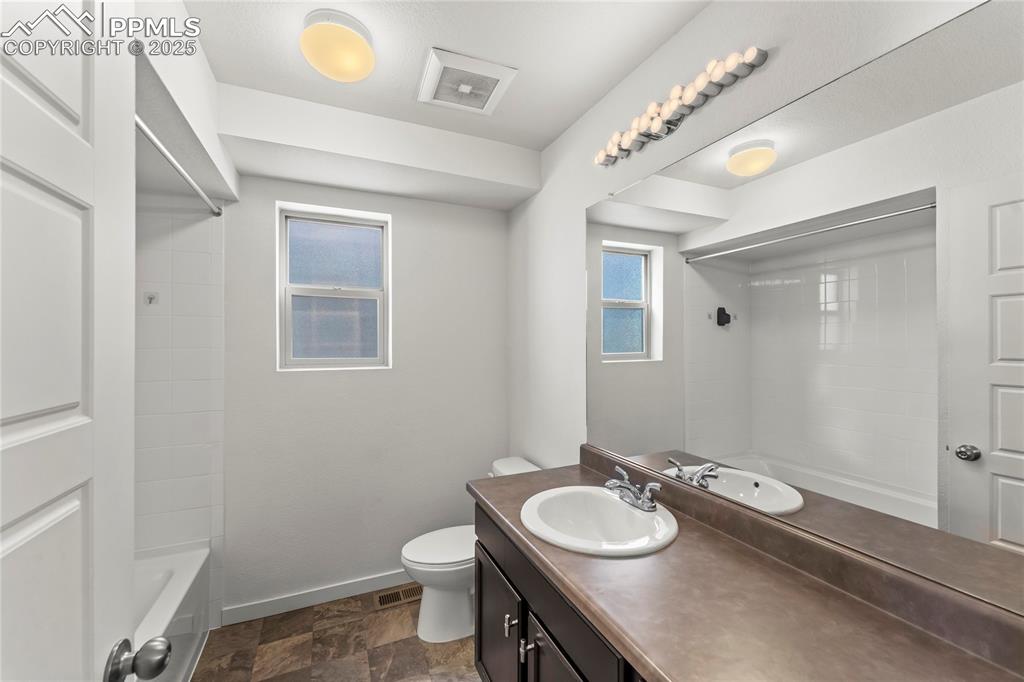 Full bath featuring vanity, bathtub / shower combination, and stone finish flooring