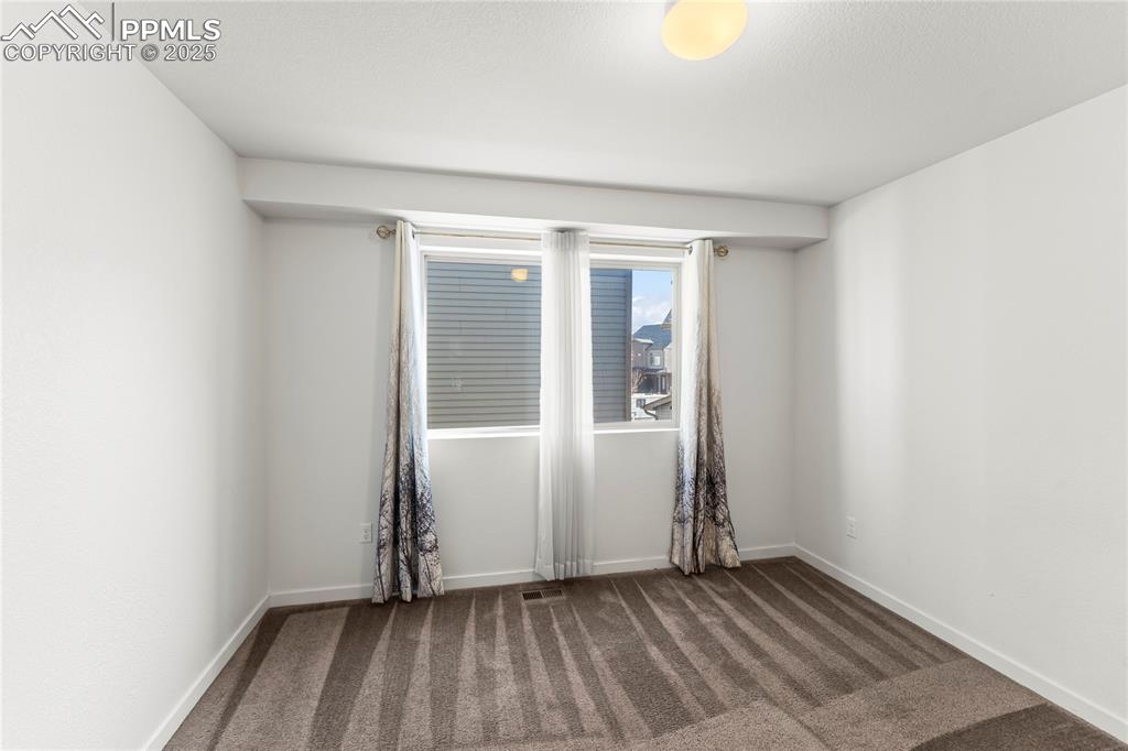 Empty room with dark colored carpet and baseboards