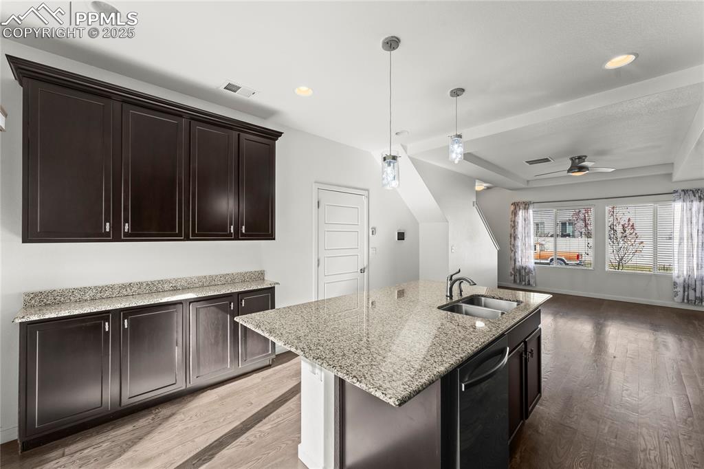 Kitchen with pendant lighting, light wood finished floors, light stone counters, dishwasher, and recessed lighting