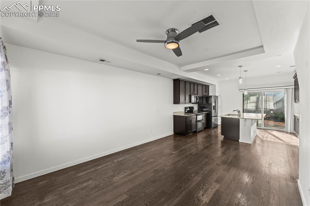 Kitchen with dark wood-type flooring, range with two ovens, decorative light fixtures, light stone counters, and a breakfast bar area