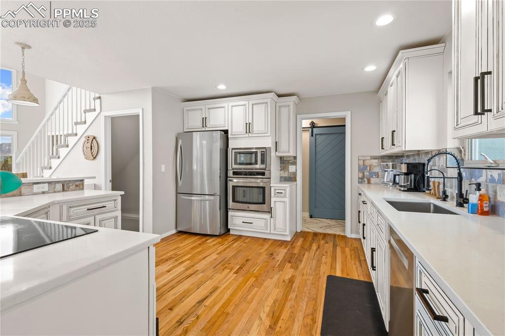 Hardwood floors in the main level in the kitchen, newer stainless steels appliances. Door on left leads to the basement and door to right leads to mudroom. 