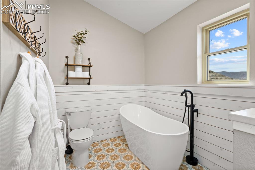 Master bathroom featuring wainscot, a soaking tub and toilet.