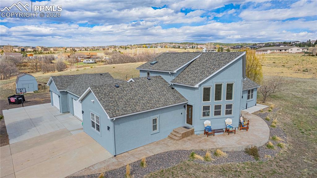 Aerial view showing the parking space, stamped concrete sidewalk and patio and storage shed. 