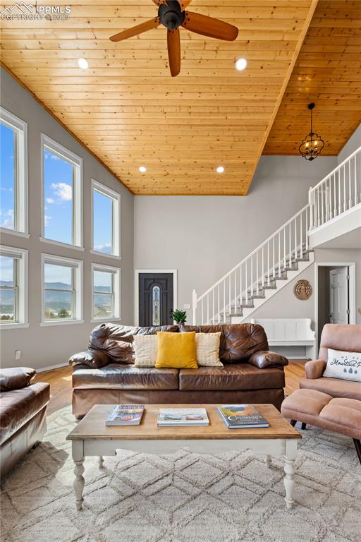 Living room with vaulted wood ceilings, fan, and large windows showing the beautiful mountain views. 