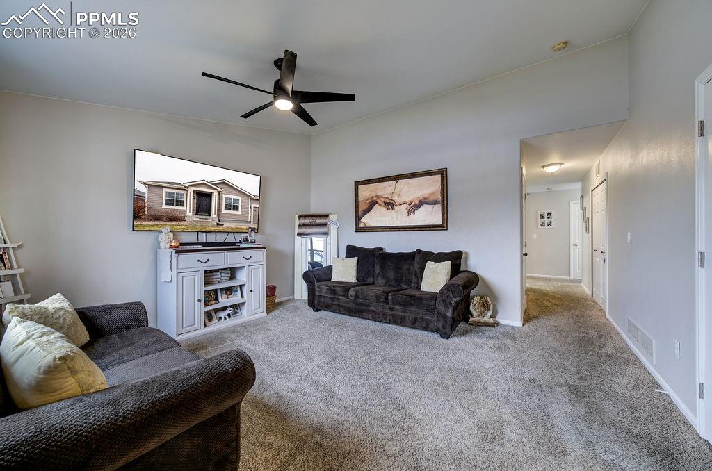 Spacious Living Room with lighted ceiling fan and neutral carpet.