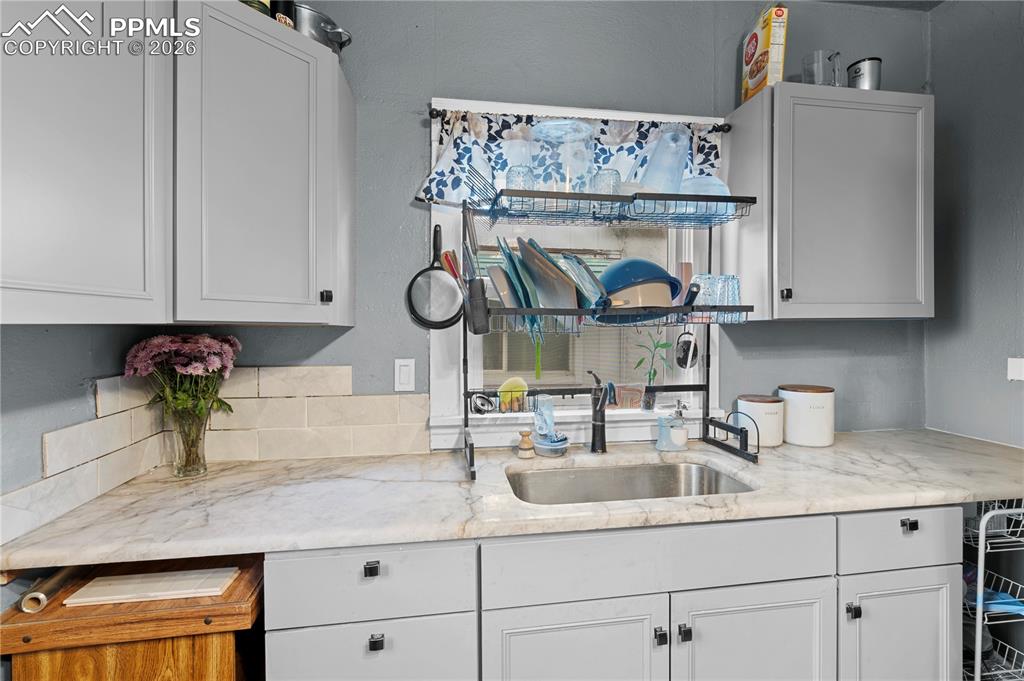 Kitchen featuring light stone countertops and white cabinetry