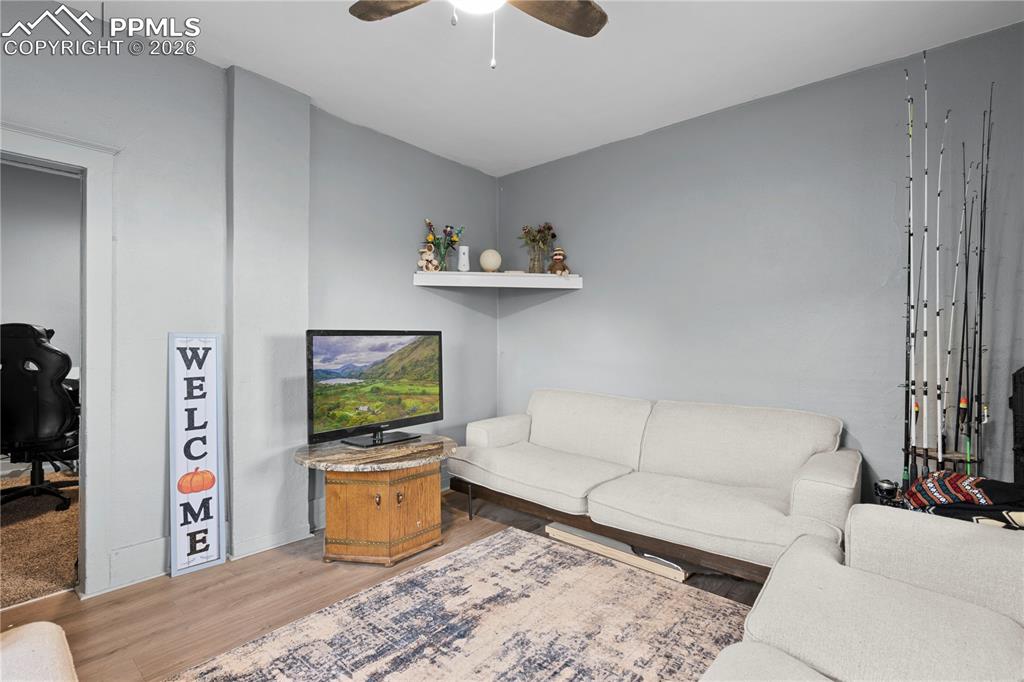 Living area featuring wood finished floors, a ceiling fan, and an office area