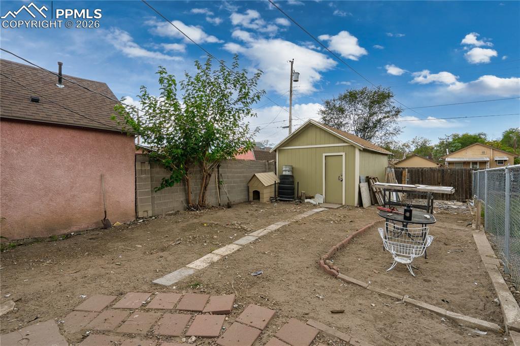 Fenced backyard featuring a shed