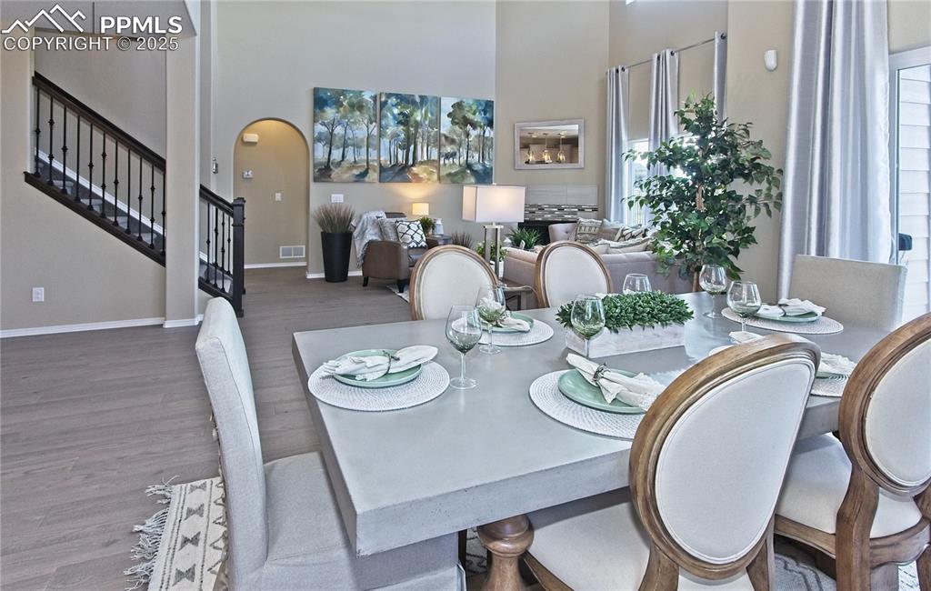 Dining space with stairs, wood finished floors, arched walkways, and a towering ceiling