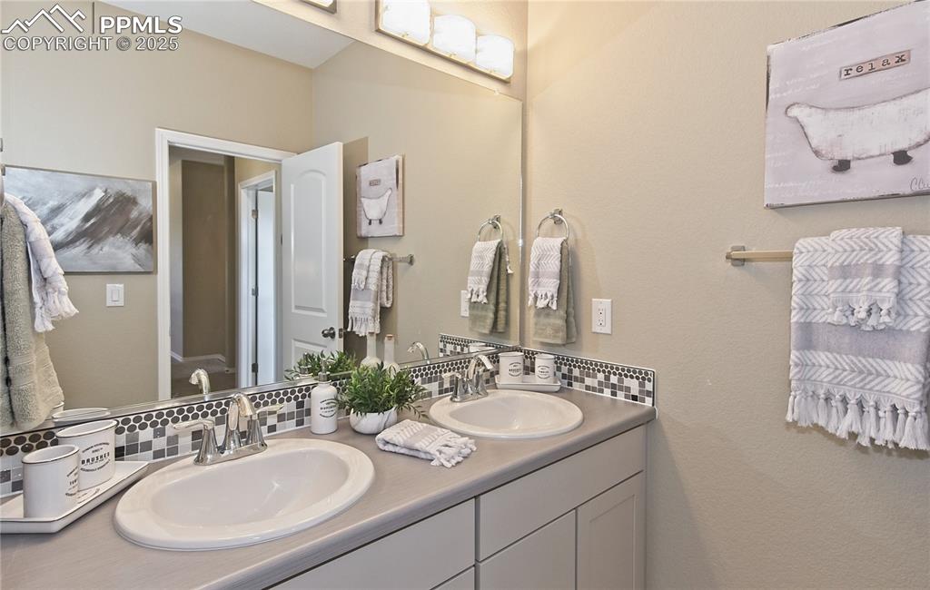 Bathroom with tasteful backsplash, double vanity, and a textured wall