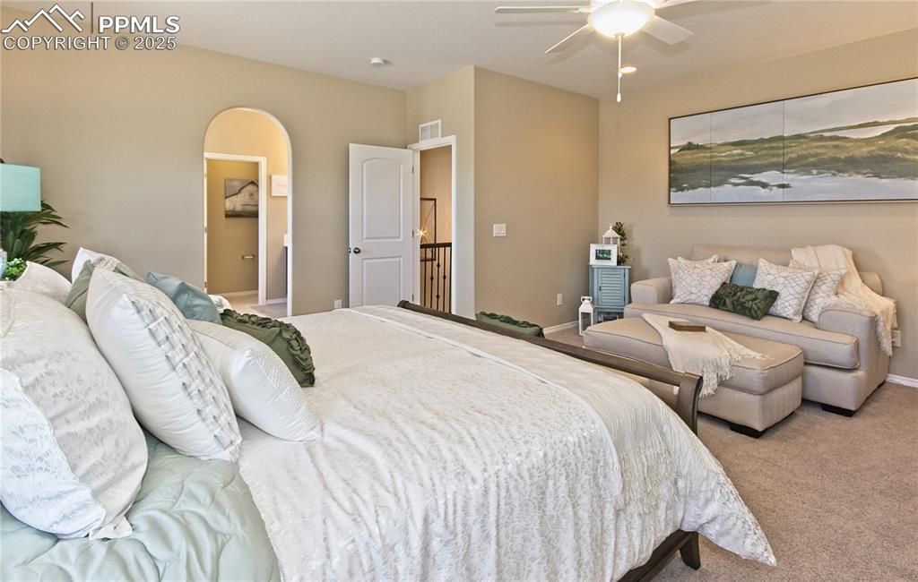 Bedroom with carpet flooring, ceiling fan, and arched walkways