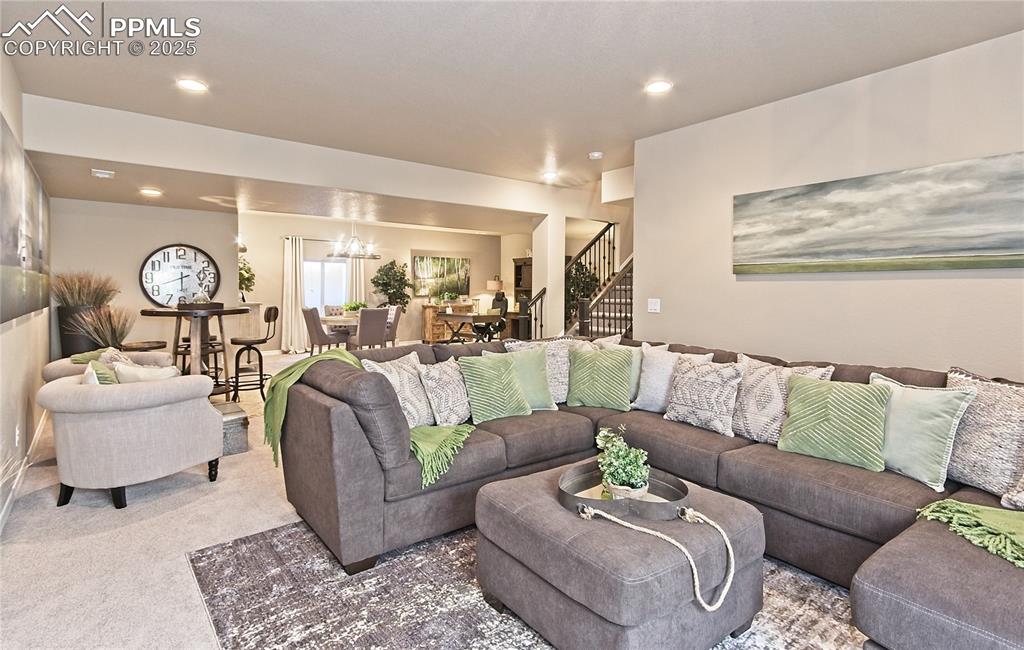 Living area with stairway, carpet, a chandelier, and recessed lighting