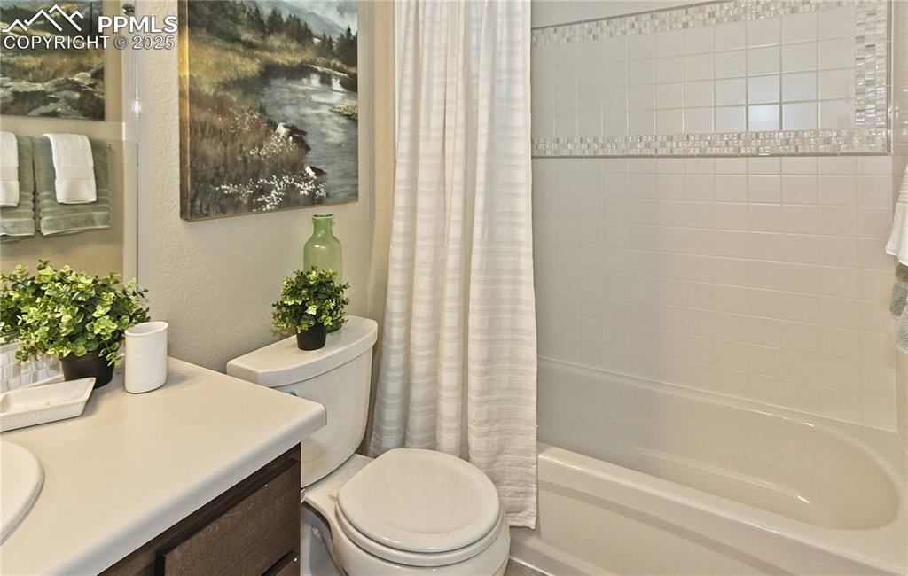 Full bath featuring shower / tub combo with curtain, vanity, and a textured wall