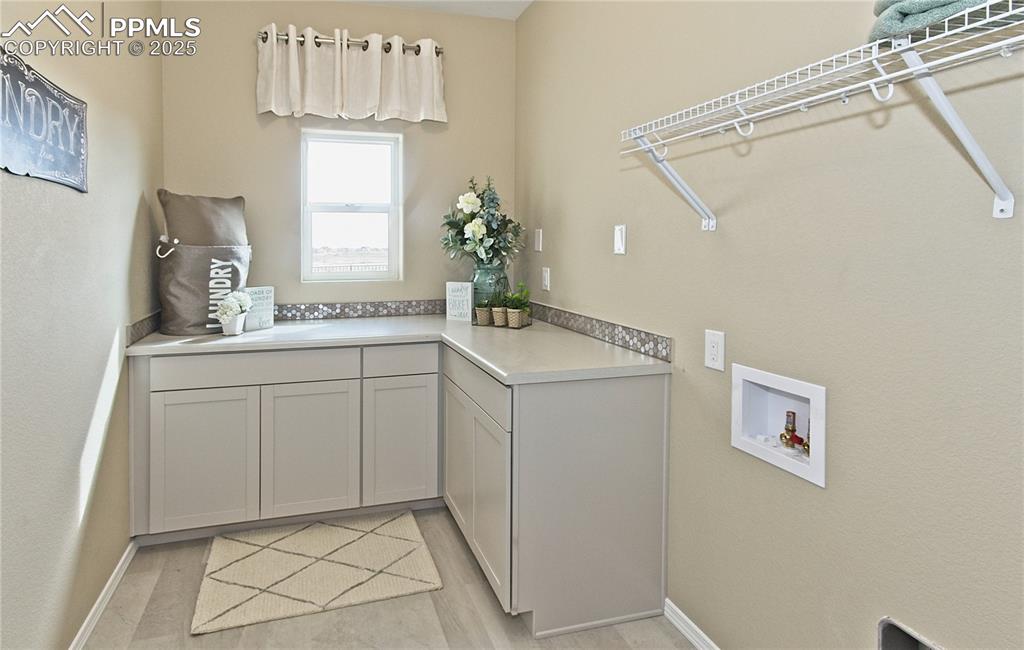 Washroom with hookup for a washing machine, cabinet space, and a textured wall