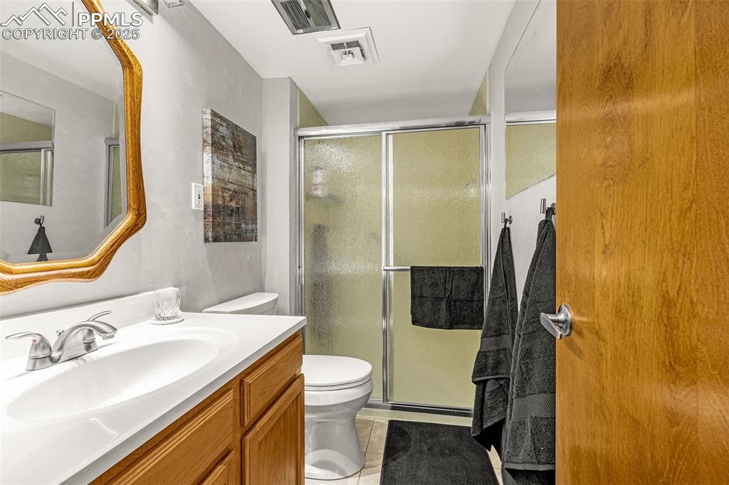 Ensuite primary bedroom includes walk-in shower, newer vanity and tile flooring