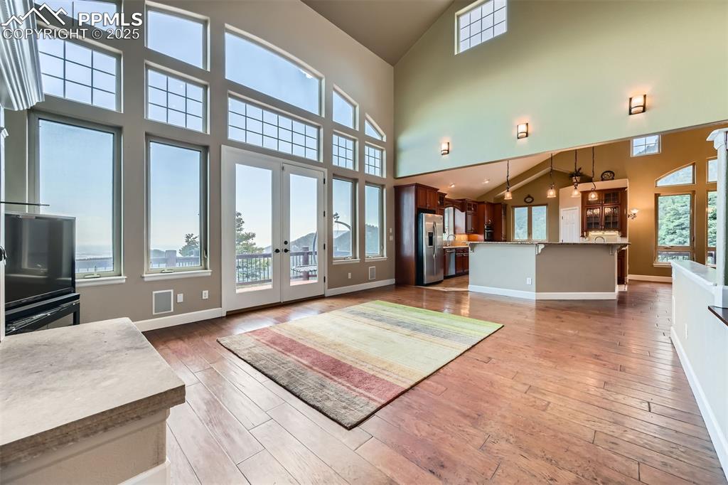 Unfurnished living room featuring high vaulted ceiling, French doors, and wood-style flooring