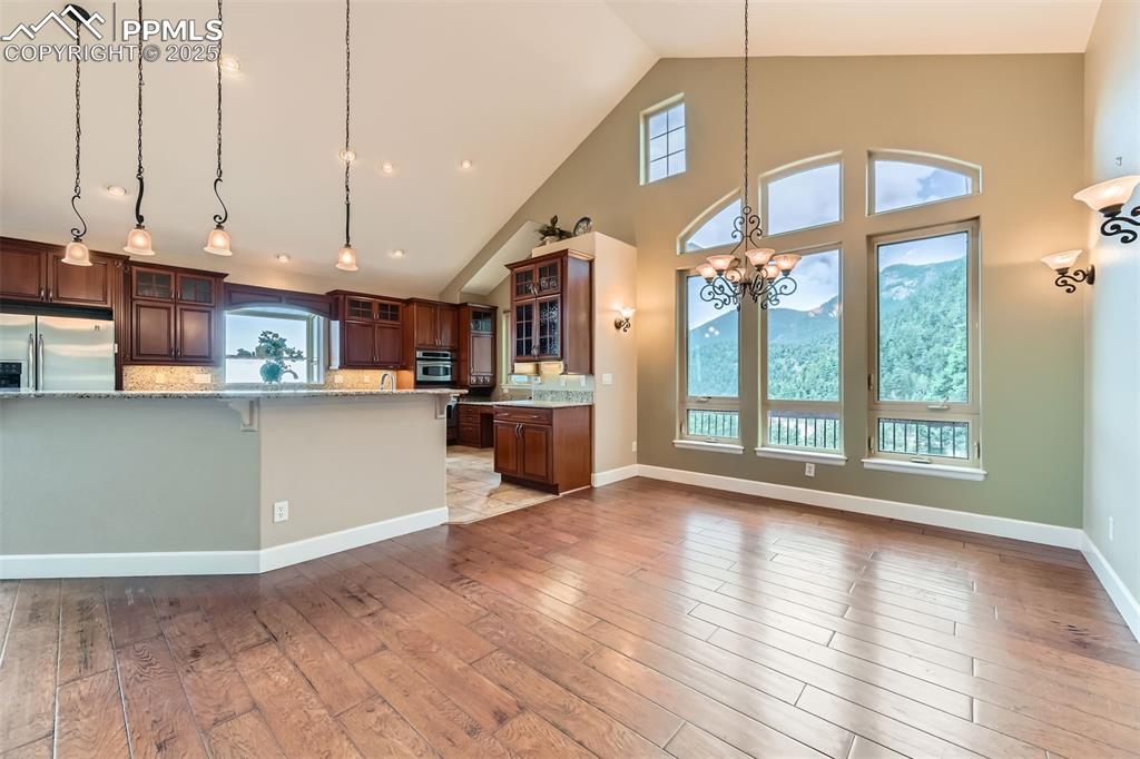 Kitchen with stainless steel appliances, a chandelier, pendant lighting, wood finished floors, and glass insert cabinets
