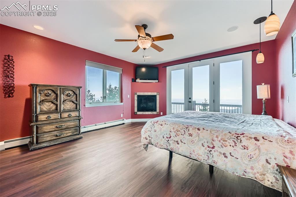 Master bedroom with access to deck, and baseboard heating unit, and a ceiling fan