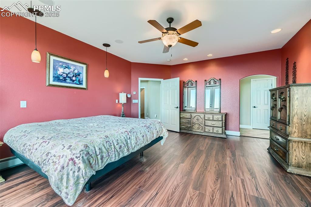 Master bedroom with arched walkways, ceiling fan, and recessed lighting