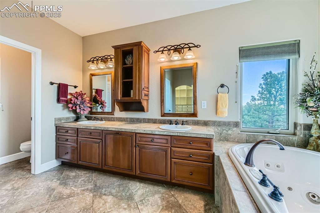 5 piece master bathroom featuring double vanity and a whirlpool tub